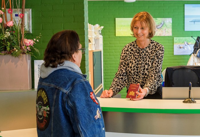 Baliemedewerker geeft paspoort aan een inwoner