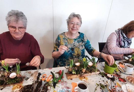 Drie vrouwen die een bloemstukje knutselen