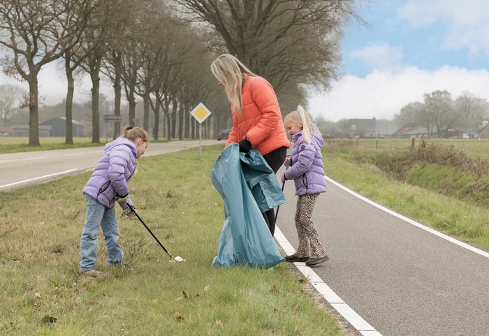 Gezin afval aan het prikken in de berm van fietspad