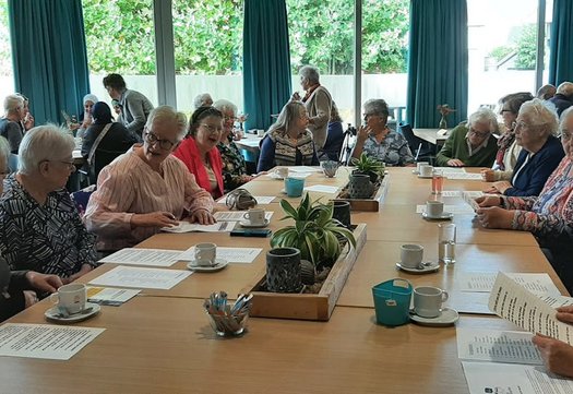 Een groep dames aan tafel met papieren voor zich