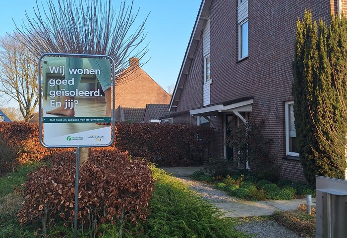 bord "wij doen mee met de isolatieactie" in tuin bij huis